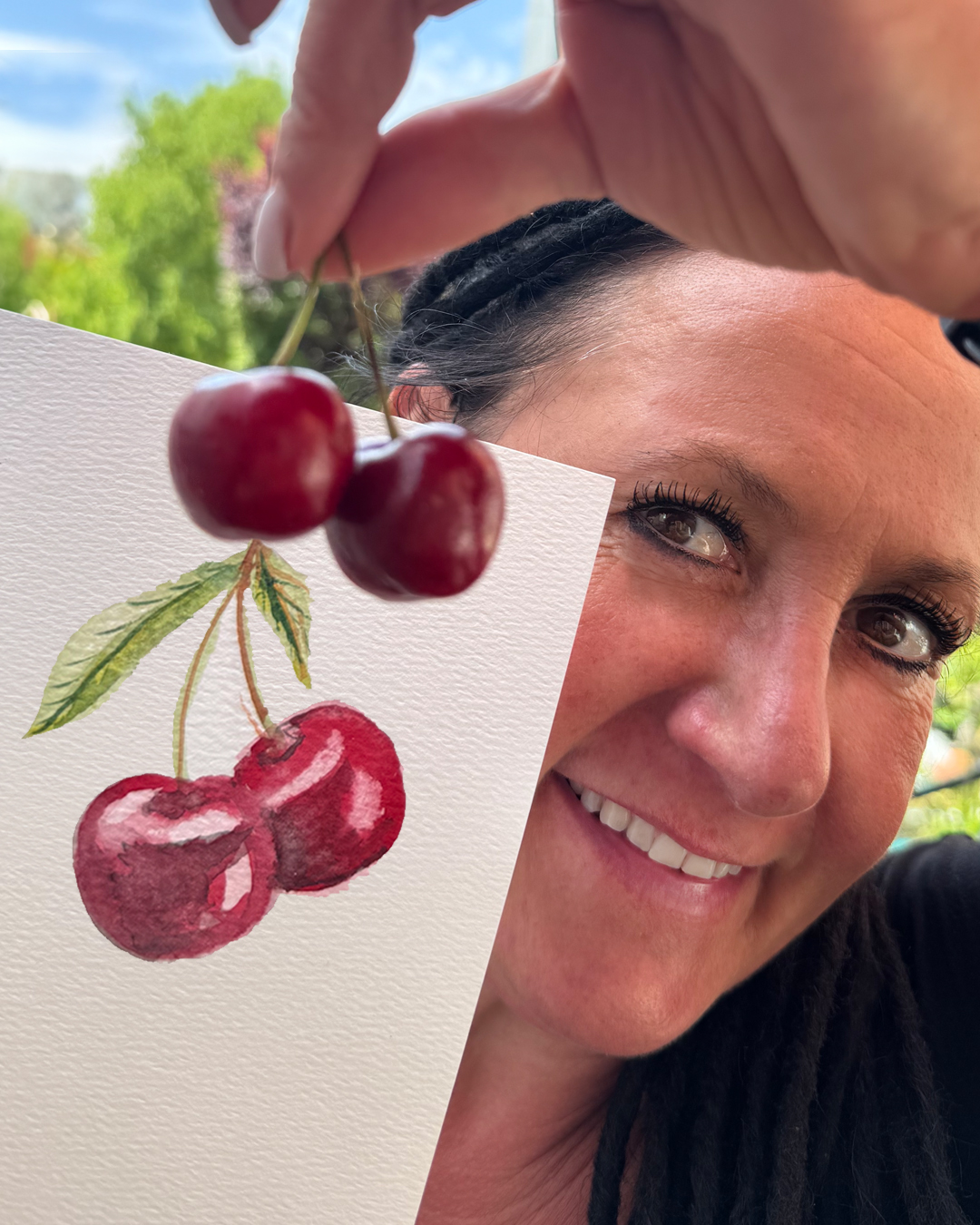 Nicole zeigt als Beispiel für ihren Aquarell-Workshop ein Blatt Papier mit gemalten Kirschen